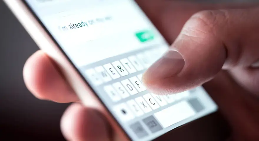 Palec pisze na smartfonie "Już jestem", potwierdzenie przybycia na wesele sms.