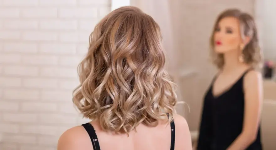 Elegancka fryzura dla świadkowej: fale na średniej długości włosach w odcieniu blondu.