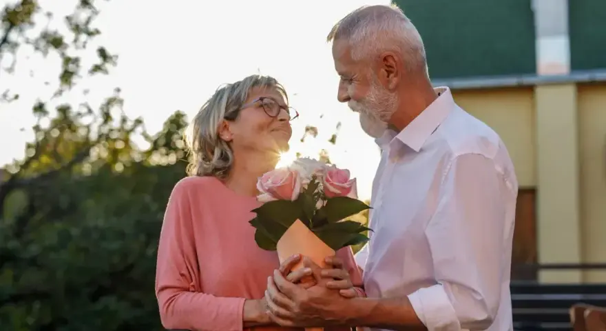 Starsza para świętuje 17 rocznicę ślubu. Mężczyzna wręcza kobiecie bukiet róż.