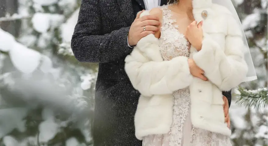 Para młoda w zimowej scenerii. Delikatny śnieg otula ich w dniu ślubu w grudniu.