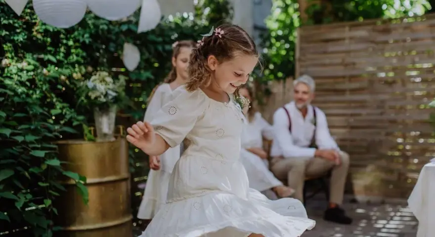Urocza fryzura dla dziewczynki na wesele, z warkoczykami i kwiatkami, idealna do tańca.