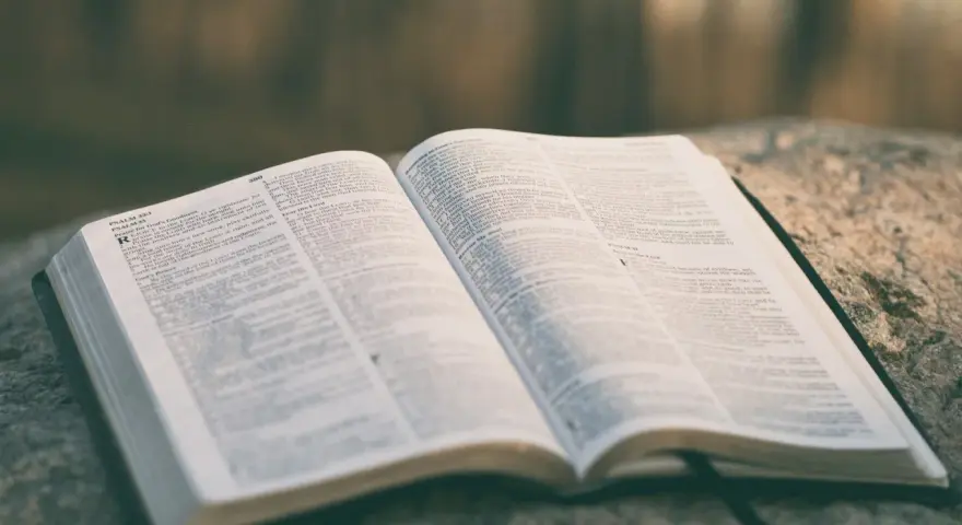 Otwarta Biblia na kamieniu, strony z tekstem, widoczny psalm 33:1. Może to być psalm ślubny.