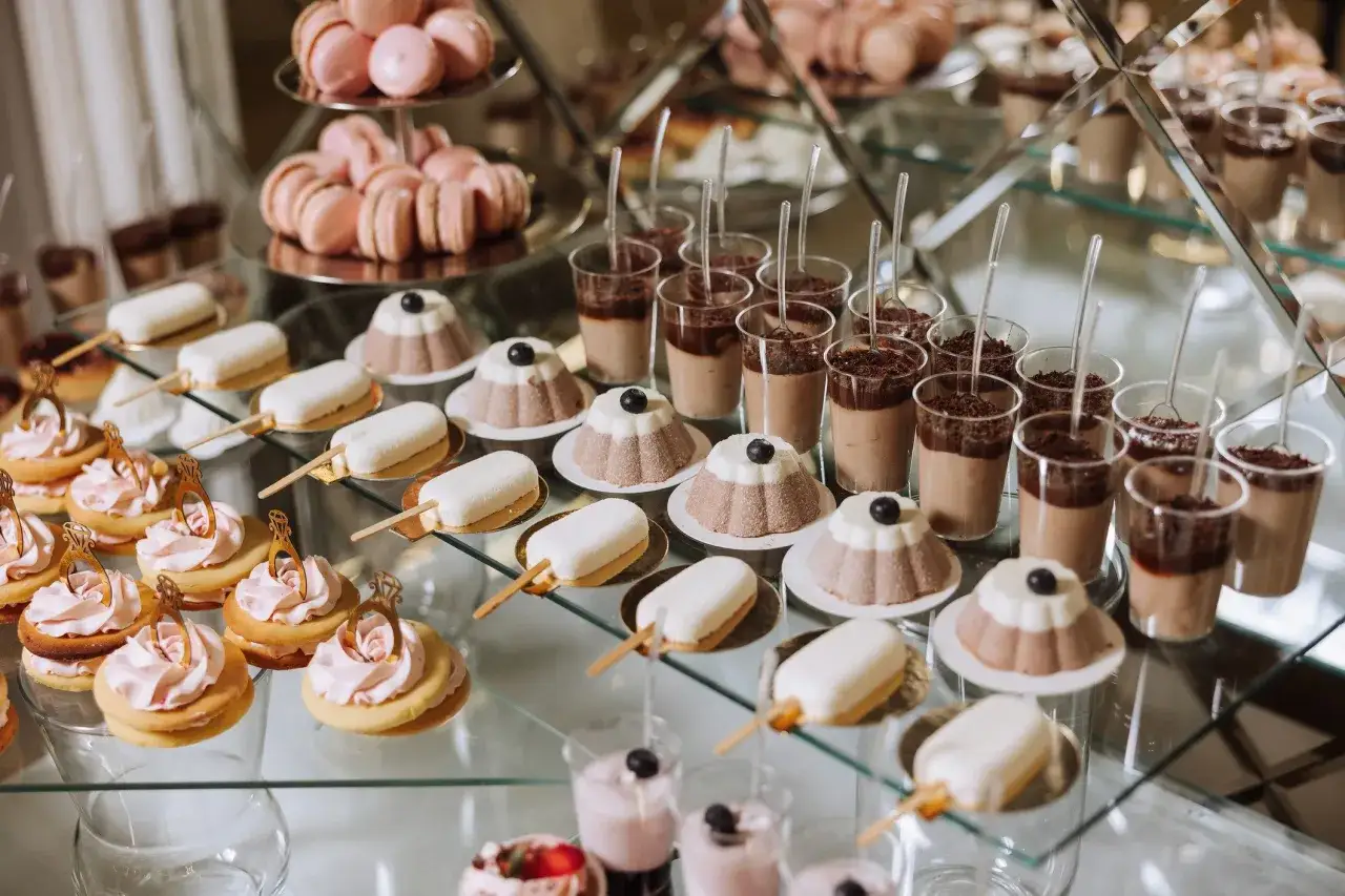 Słodki stół weselny: różowe makaroniki, ciasteczka z kremem i pierścionkami, deserki w pucharkach i cake pops wesele.