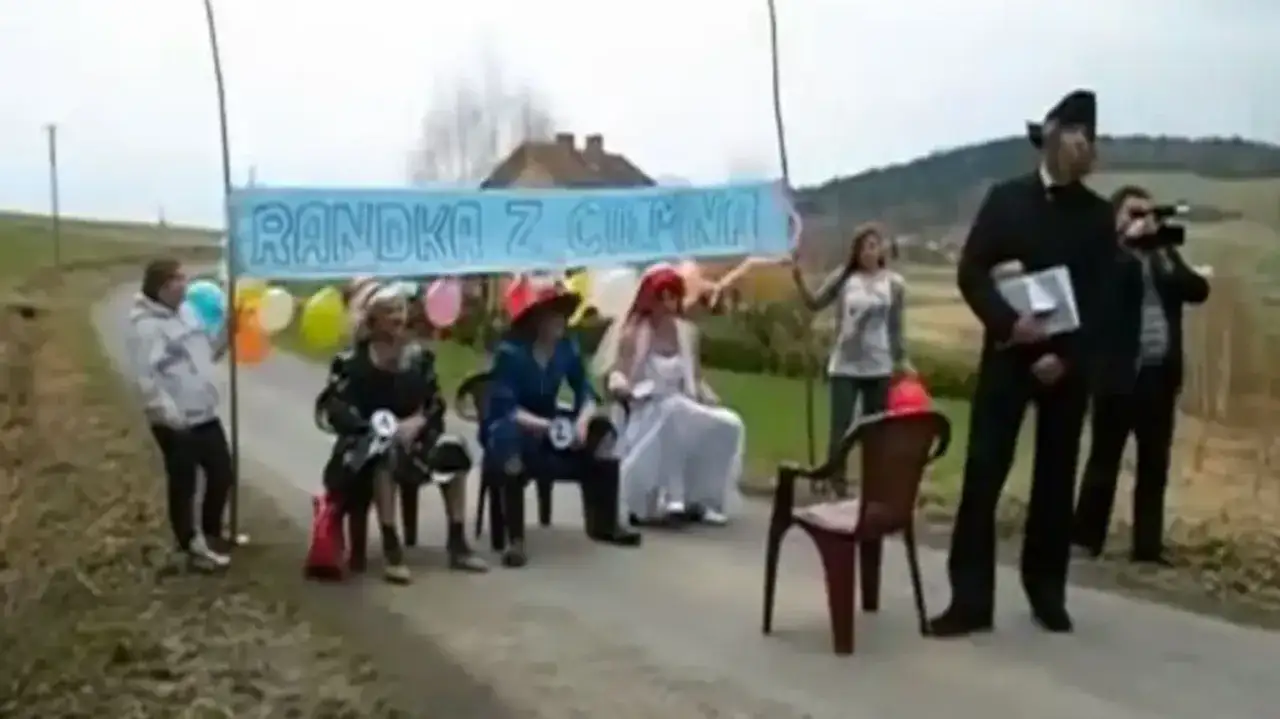 Na bramie weselnej widać grupę osób, balony i transparent