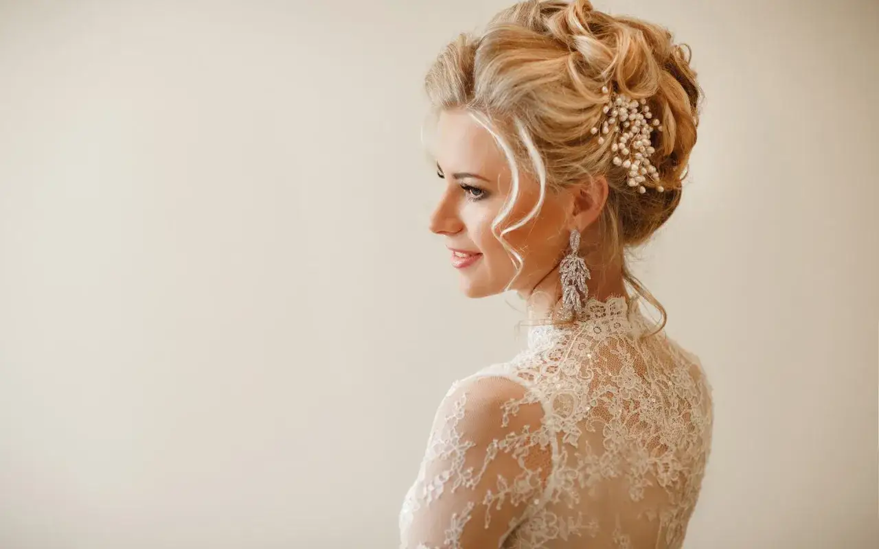 Elegancka fryzura do długiej sukienki na wesele, z perłowym zdobieniem i długimi kolczykami.