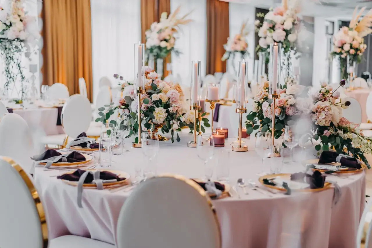Eleganckie nakrycia stoł&oacute;w z kwiatami i świecami. Idealna sceneria na wesele w piątek.