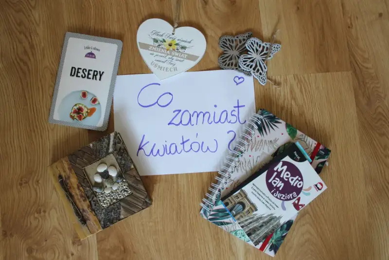 Co zamiast kwiatów na wesele? Na stole leżą karty z deserami, książki o podróżach i serce z napisem "Niech Twój uśmiech zmienia świat".
