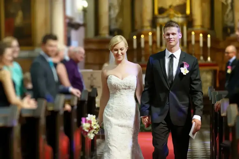 Para młoda idzie do ołtarza. Piękna suknia ślubna i elegancki garnitur świadczą o tym, że to wyjątkowy ślub po 40.