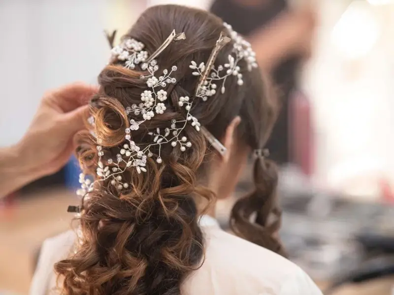 Eleganckie fryzury ślubne z perłami i kryształkami, tworzące romantyczny wianek na brązowych włosach.